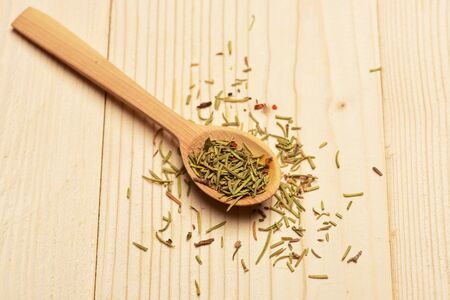 aromatic rosemary in spoon used in cuisine on lactic vintage wooden background, side viewの写真素材