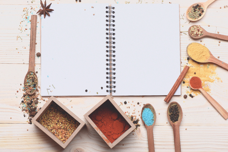 set of ingredients for cooking spicy fragrant spices in spoons with boxes and coriander, pepper, curry, cinnamon, salt and notebook on vintage wooden background , copy spaceの写真素材