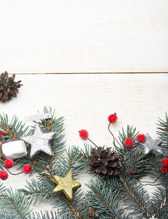 christmas or new year decoration with green fir tree with silver golden stars, pine cone and marshmallow on white vintage wooden background, copy spaceの写真素材