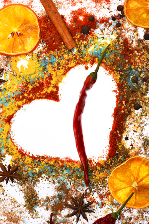valentine set of ingredients for cooking spicy fragrant spices in spoons with coriander and pepper, laurel sheet, chili pepper, paprika in form of heart isolated on white background, copy spaceの写真素材