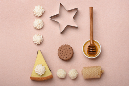 set of poppy pie near honey and stick, tasty coconut candies, honeycomb and white marshmallows with silver star and chocolate cookies on colorful pink background, top viewの写真素材