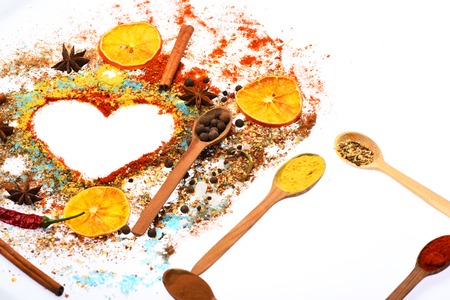 valentine set of ingredients for cooking spicy fragrant spices in spoons with coriander and pepper, laurel sheet, chili pepper, paprika in form of heart isolated on white background, copy spaceの写真素材