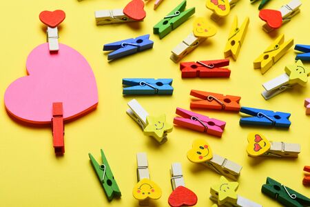 set of colorful clothespins with different emotions and valentine pink heart or card on yellow backgroundの写真素材
