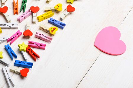 set of colorful clothespins with selective focus with big pink valentine heart or card on white...