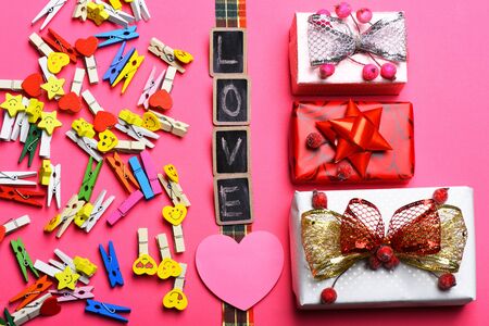 set of colorful clothespins with different emotions, valentine card and black boards with word Love and presents or gifts on pink backgroundの写真素材