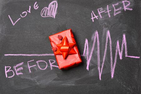 word Love Before After and cardiogram painted by pink chalk and red present or gift with big bow on black board background, top viewの写真素材