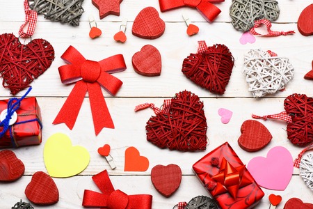 set of colorful decorative valentine hearts with checkered ribbon, red present or gift and cute bows on white vintage wooden backgroundの写真素材