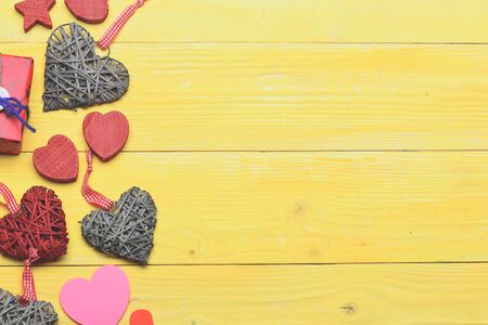 set of colorful decorative valentine hearts with checkered ribbon, red present or gift on yellow wooden background, copy spaceの写真素材