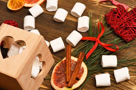 set of valentine decorative hearts, marshmallows, cinnamon and dry orange on brown vintage wooden backgroundの写真素材