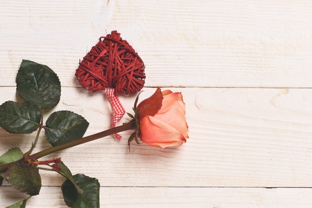 decorative colorful valentine red heart with checkered ribbon and beautiful orange rose on white vintage wooden backgroundの写真素材
