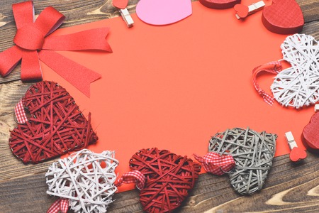 set of colorful decorative valentine hearts with checkered ribbon, cute bow, pegs and red sheet paper on brown vintage wooden background, copy spaceの写真素材