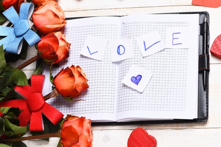 beautiful valentines day set with roses, bows, heart symbol with notebook on vintage wooden background, top viewの写真素材