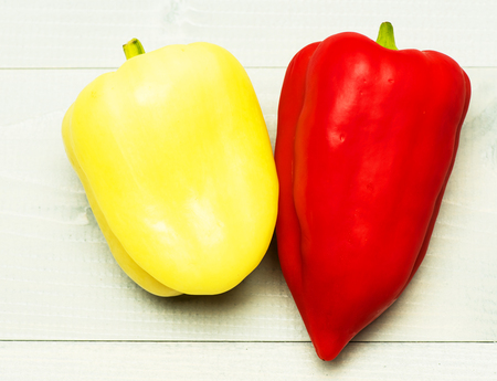 red and yellow fresh peppers on white vintage wooden backgroundの写真素材