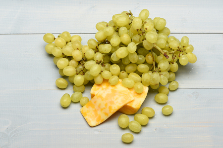 bunch of green fresh grapes and pieces of marbled cheese on blue vintage wooden backgroundの写真素材