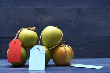 Set of pyramid green fresh apples with colorful tags on blue vintage wooden background, copy spaceの写真素材