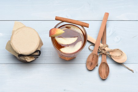 Set of glass of apple juice with different types of nuts in glass jar covered craft paper, cinnamon and spoons with string on light blue vintage wooden background, top viewの写真素材