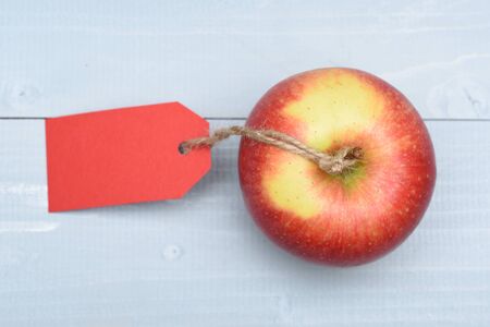 Fresh red apple with red tag and string on vintage wooden background, copy spaceの写真素材