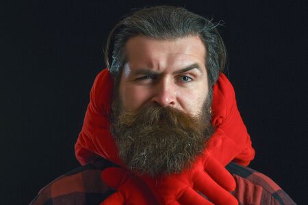 handsome bearded man or guy in checkered shirt with fashionable mustache and beard on serious face, with decorated hands of valentines red heart pillow on black backgroundの写真素材
