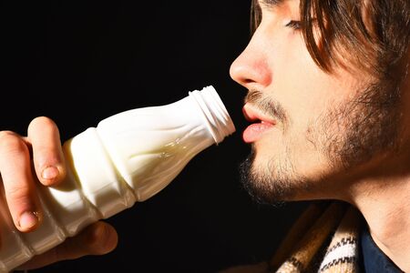 handsome bearded man in checkered plaid drink kefir or yogurt on black studio background, close upの写真素材