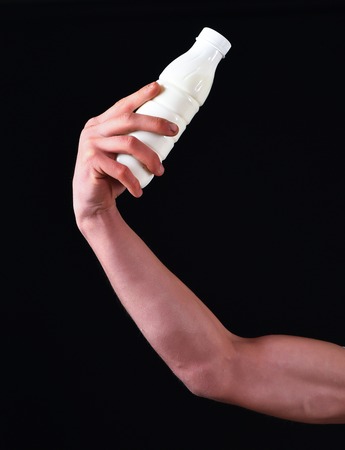 male naked hand holding kefir or yogurt in studio on black studio backgroundの写真素材