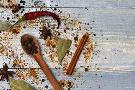 set of various aromatic spices of black pepper with spoon, bay leaf, cinnamon, chili peppers and anise on vintage wooden blue background, copy spaceの写真素材