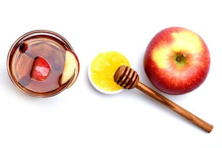 hot drink of apple tea with cinnamon spice stick or mulled wine in glass and wooden honey spoon isolated on white backgroundの写真素材