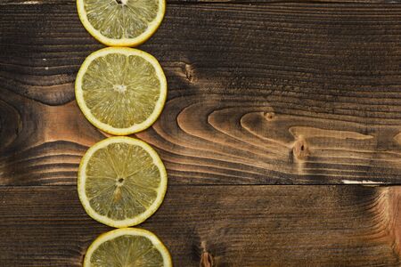 set of colorful fresh yellow lemon slices in row on brown wooden vintage background, copy spaceの写真素材