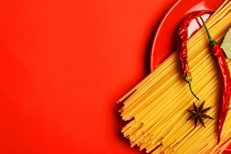 italian pasta with chili pepper and badian on red background as cooking products, copy spaceの写真素材