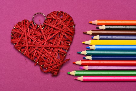 decorative red heart and colored pencils on pink background, top viewの写真素材
