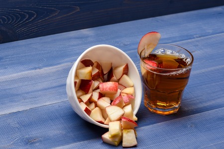 set of glass with juice and dish with pieces of apple on blue vintage wooden background, side viewの写真素材