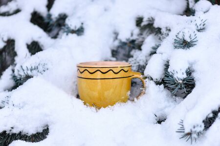 yellow ornamented with waves cup outdoor on snowy firry tree branches on natural background, selective focusの写真素材