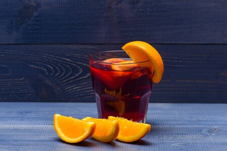 hot drink of mulled wine or tea with spice and orange fruit in glass on white grey wooden backgroundの写真素材