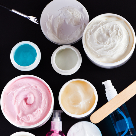 set of various cosmetics: cream, nourishing cream, gel, cleanser, brushes, nail file, cosmetic spatula isolated on black background, top view, closeupの写真素材