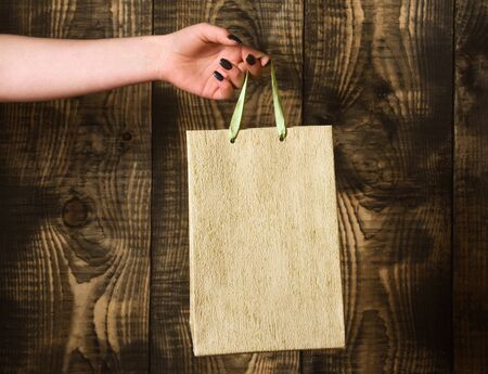 golden color paper shopping bag or textured package in female hand as holiday present or gift on...