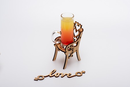 alcohol cocktail in glass: sex on the beach on little decorative chair with love inscription isolated on white background, side viewの写真素材