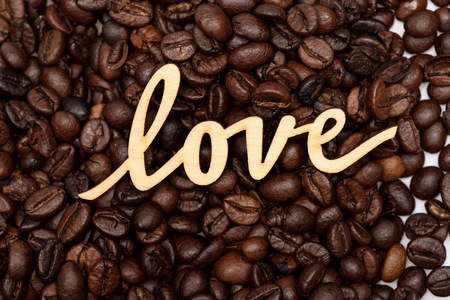 wooden inscription of word love on roasted brown coffee beans backgroundの写真素材