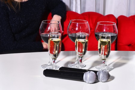White and red wine, alcoholic drink, beverage, served in different glasses and two wireless microphones on white tableの写真素材