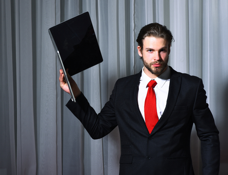 caucasian hipster with moustache with computer, laptop has serious face, unshaven guy with stylish hair in suit and red tieの写真素材
