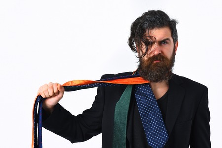 caucasian hipster with moustache in black suit holding ties around neck isolated on white studio...