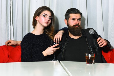 Romantic couple of pretty girl or beautiful woman drinking red wine in glass and bearded man,...
