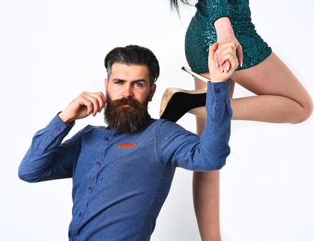 caucasian hipster with moustache on serious face with female sexy legs in fashionable shoes and green sequins skirt isolated on white background getting haircutの写真素材