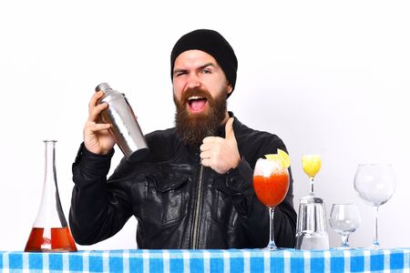 caucasian hipster with moustache in rock black style holding shaker and glasses of alcoholic cocktails with shot on blue checkered plaid isolated on white backgroundの写真素材