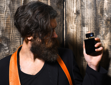 caucasian hipster with moustache have acid orange tie on suit and holding perfume on brown vintage wooden studio backgroundの写真素材