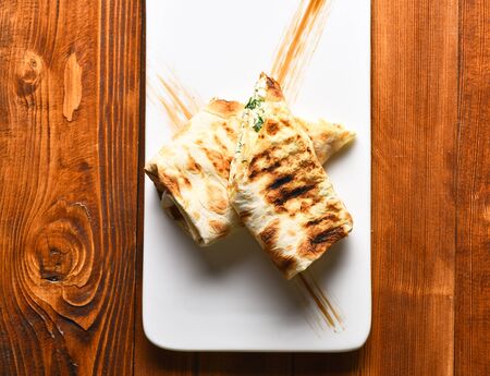 Tasty bread, lavash or pita, roasted rolls, stuffed with cheese and green herbs served on white...
