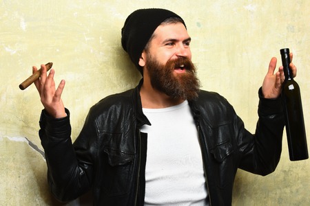 Bearded man, long beard. Brutal caucasian smiling happy unshaven hipster holding bottle and smoking...