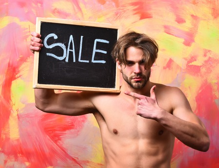 Bearded man, short beard. Caucasian sexy macho man with moustache show six packs and abs on muscle torso on athletic body holding board on colorful studio background, copy spaceの写真素材