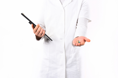 Male hands of caucasian doctor or postgraduate student holding clipboard and pills in medical gown isolated on white studio background. Medicine conceptの写真素材