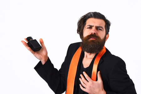 Bearded man, long beard. Brutal caucasian satisfied hipster with moustache have acid orange tie on suit and holding perfume isolated on white studio backgroundの写真素材