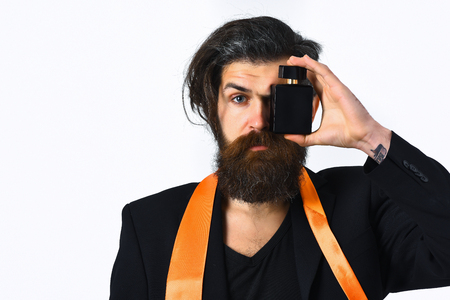 Bearded man, long beard. Brutal caucasian hipster with moustache have acid orange tie on suit and holding perfume isolated on white studio backgroundの写真素材