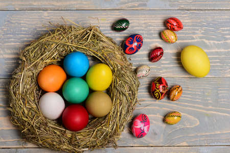 set of colorful eggs inside straw nest and painted with ornaments on grey vintage wooden background. Happy Easter concept, top viewの写真素材